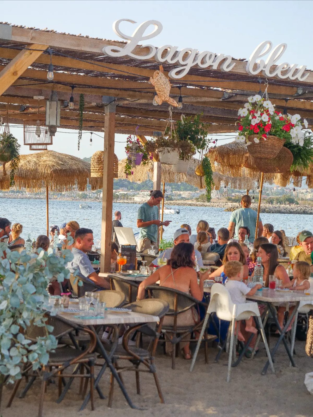 Terrasse pleine au crépuscule avec enseigne Lagon bleu